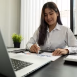 A woman sitting at an office desk writing