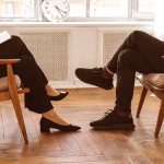 A clinician and client facing each other in a session sitting in wooden armchairs