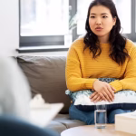 A woman in a yellow top sitting in a therapy session