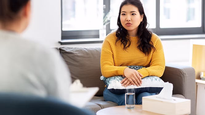 A woman in a yellow top sitting in a therapy session