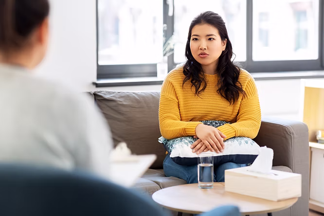 A woman in a yellow top sitting on a lounge at a therapy session