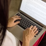 Hands typing on a laptop