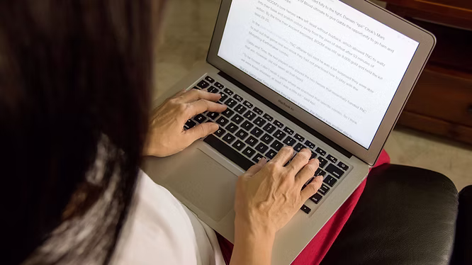 Hands typing on a laptop