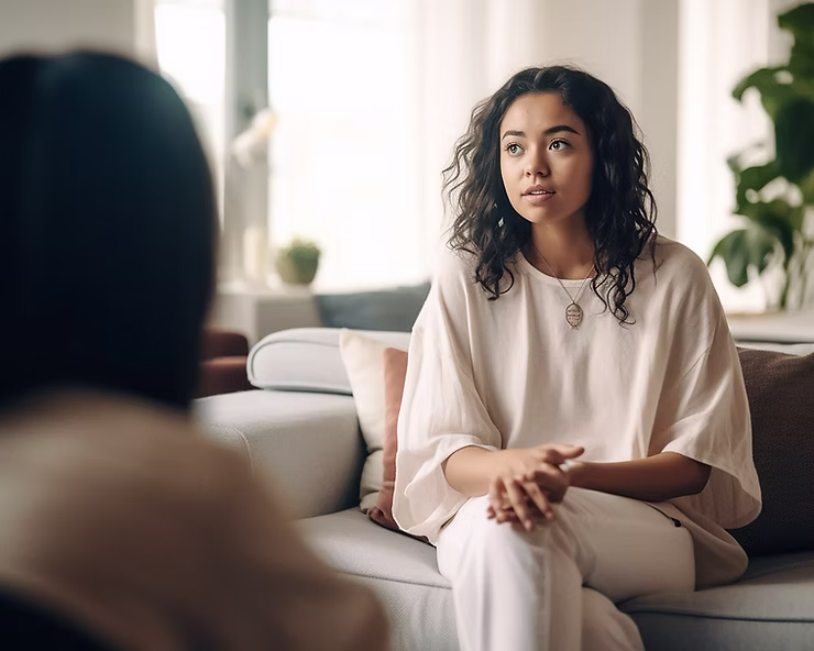 A person sitting on a grey lounge during a therapy session