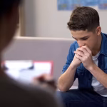 A young man with his face in his hands during a session