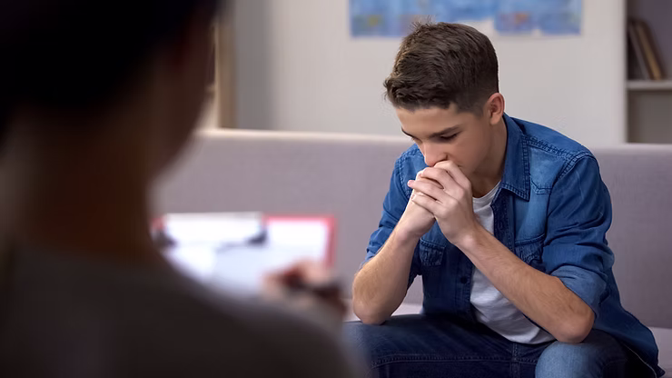 A young man with his face in his hands during a session