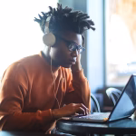 A person with headphones working on a laptop