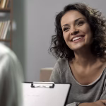 A woman sitting across from a clinician smiling