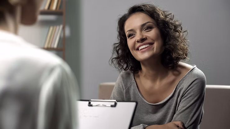 A woman sitting across from a clinician smiling