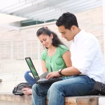 Two people sitting outside studying on a laptop