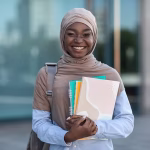 A young woman smiling holding books