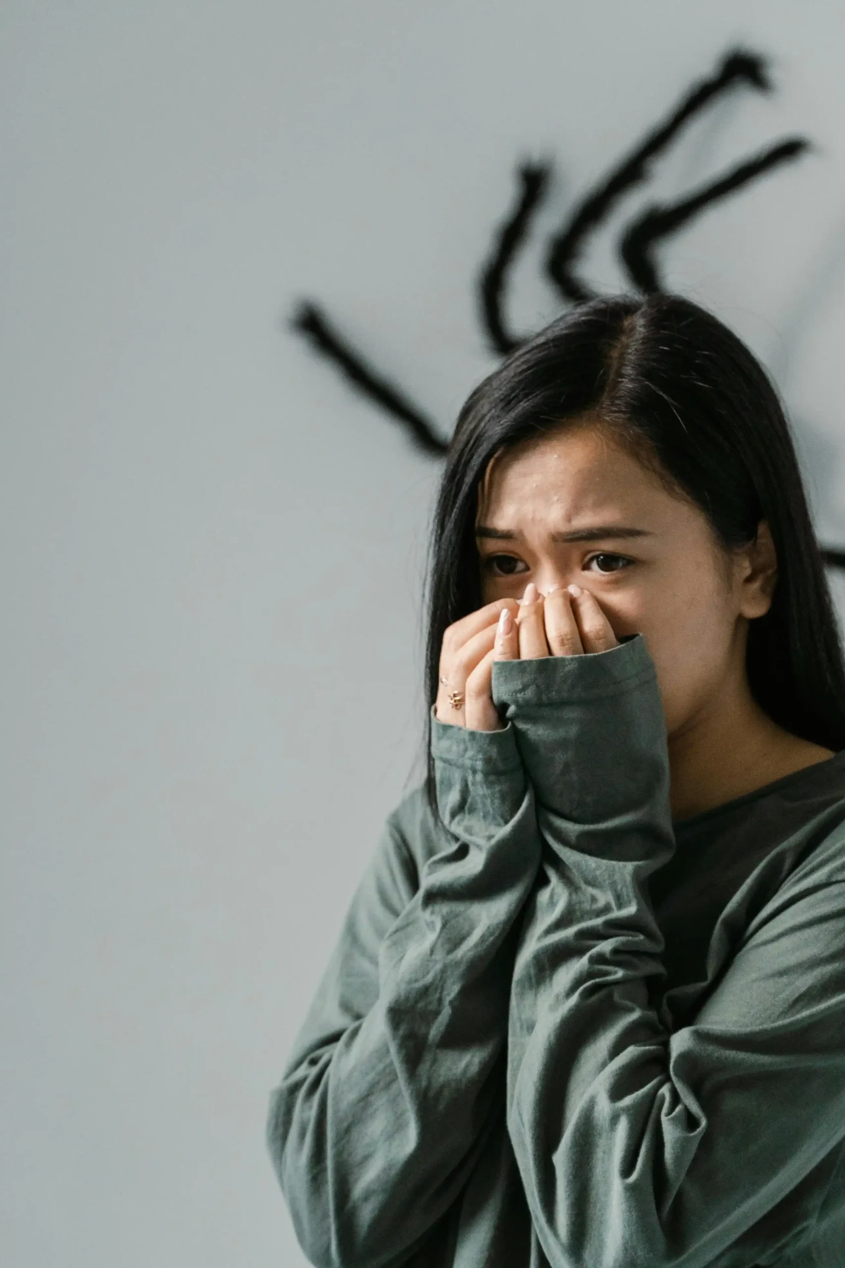 A person covering their nose and mouth with their hands appearing overwhelmed