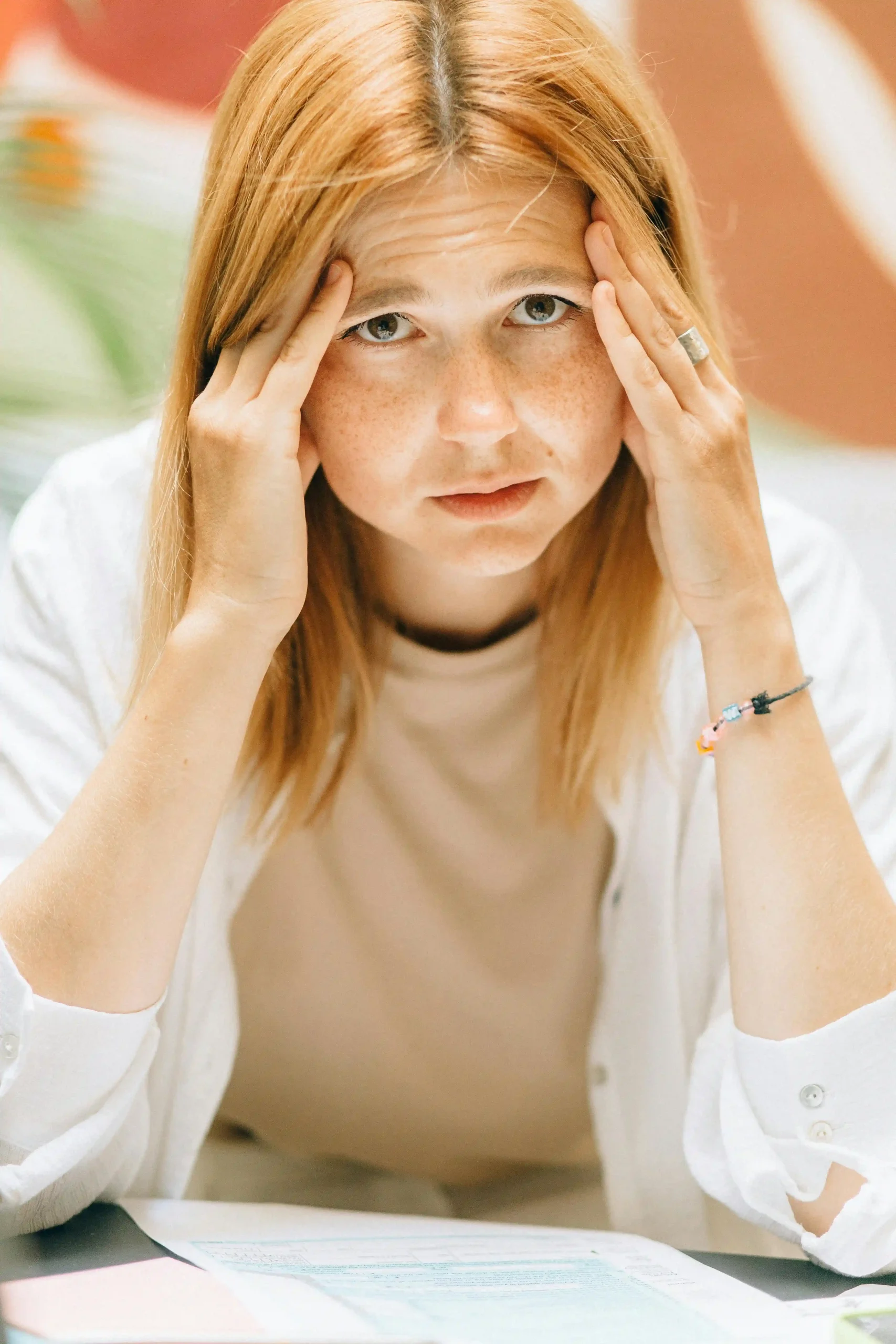 A person with their hands to their facing appearing overwhelmed